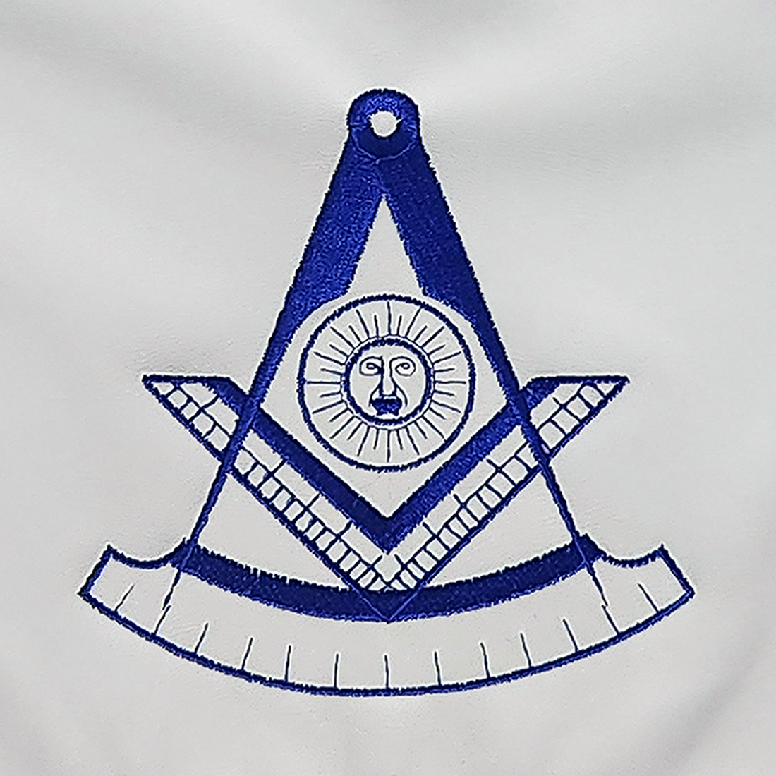 Masonic apron with machine embroidered past master symbol, featuring a square and compass with the all-seeing eye, bordered by a royal blue ribbon.
