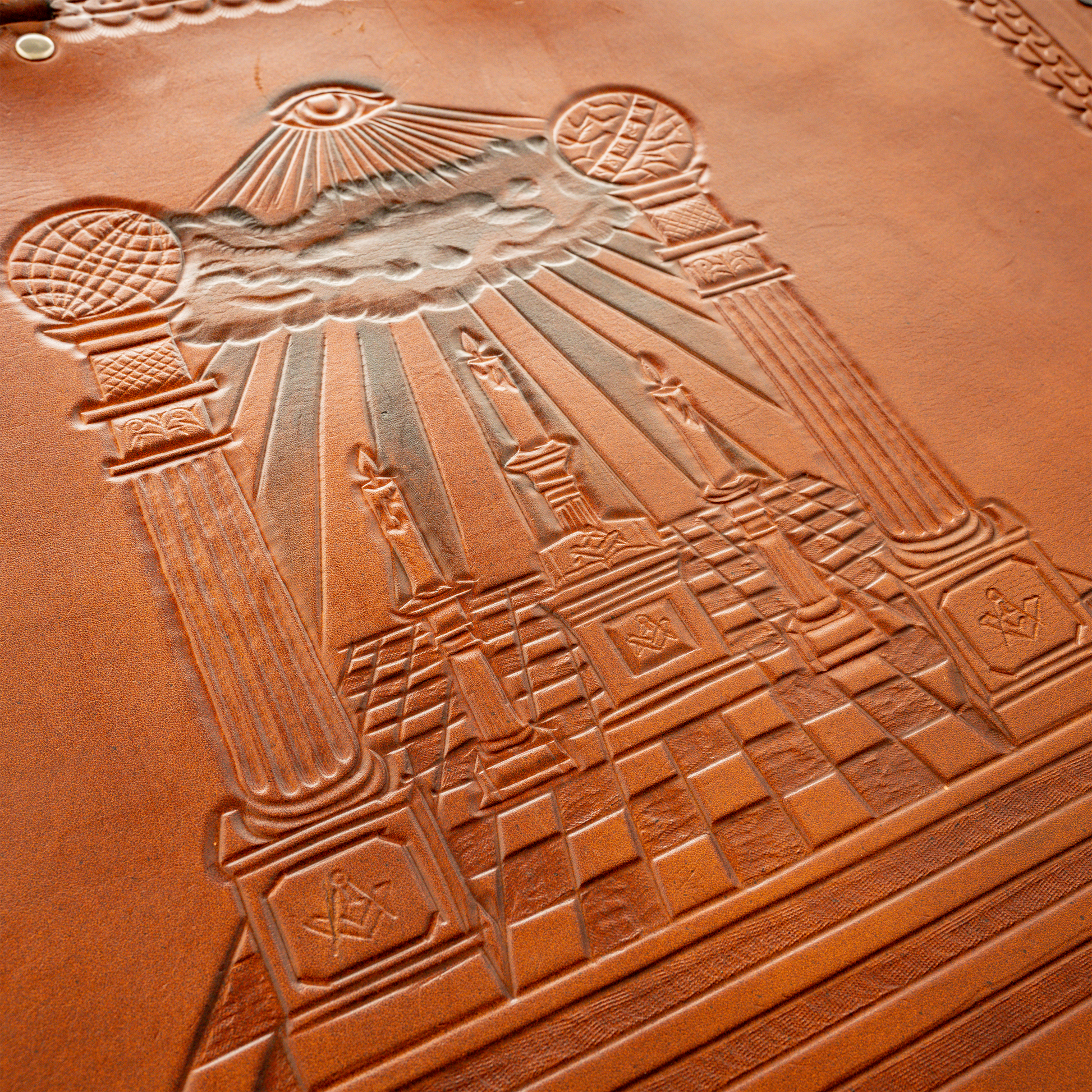 Hand-tooled leather artwork featuring Boaz and Jachin, Masonic altar and Mosaic Pavement, and three candles